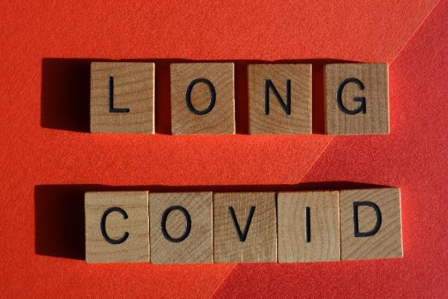 רקע אדום ועליו ומונח קורונה ארוכה המסמל את ההשלכות ארוכות הטווח של מחלת ה-Covid 19